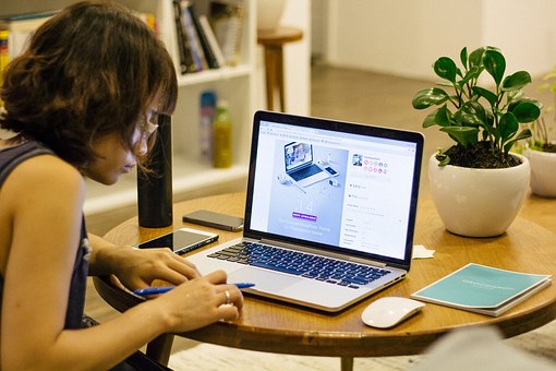 パソコンの前で勉強する女性の画像